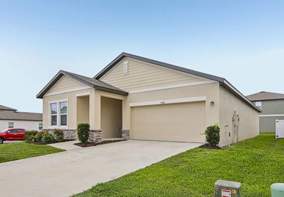 A two-story house with a garage and a red car parked in front.