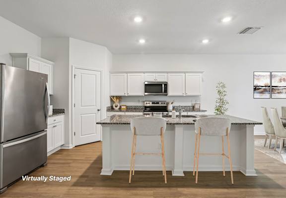 A kitchen with white cabinets and a stainless steel refrigerator.