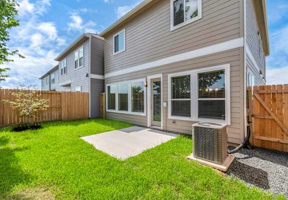 the back of a house with a yard and an air conditioner