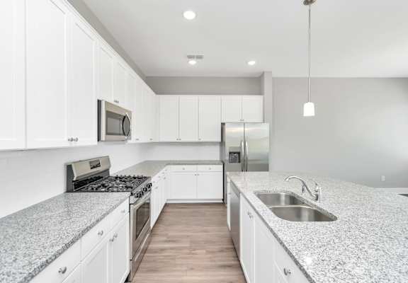 a kitchen with white cabinets and gray countertops