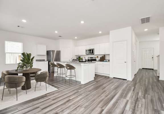 A modern kitchen with white cabinets and a wooden floor.