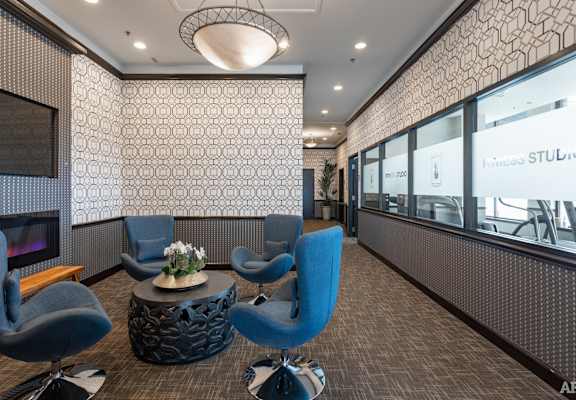 a lounge area with blue chairs and a fireplace