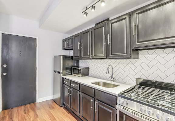 A kitchen with a black door and a black fridge.