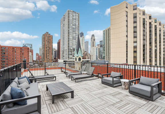 A rooftop patio with a table and chairs overlooking a city skyline.