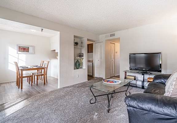 A living room with a grey couch and a glass coffee table.