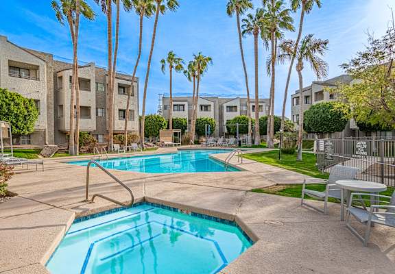 A swimming pool surrounded by palm trees and apartment buildings.