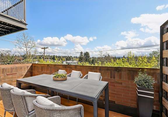 A table with chairs on a balcony with a view of the sky.