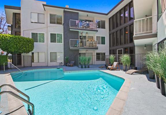 A swimming pool in front of a modern apartment building.