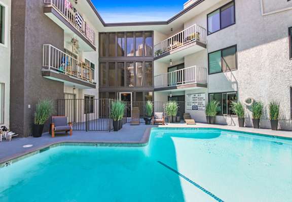 A swimming pool in front of a building with balconies.
