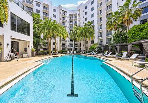 A large swimming pool in a residential area with palm trees.