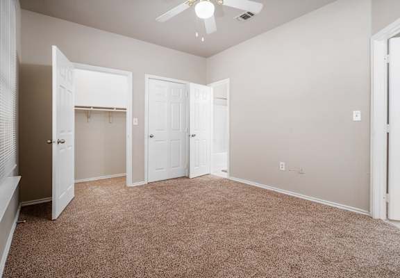 A room with a carpeted floor and a ceiling fan.