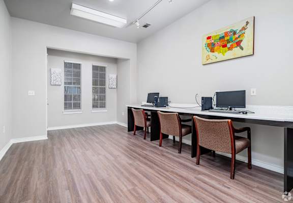 A room with a long table and chairs and a painting on the wall.