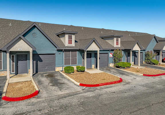 A row of houses with grey roofs and red flower beds in front.