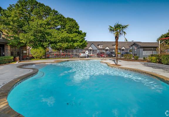 A large swimming pool surrounded by a fence and trees.