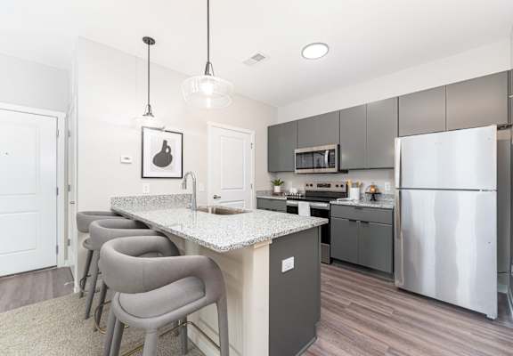A kitchen with a white counter top and grey chairs.