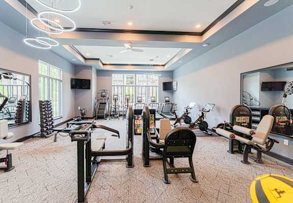 A spacious gym with various exercise equipment and mirrors.