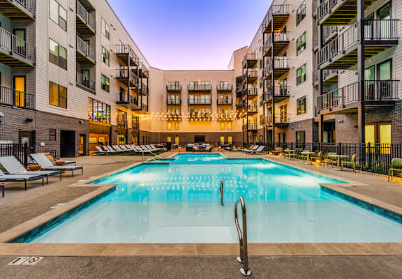 A large outdoor swimming pool in front of apartment buildings.