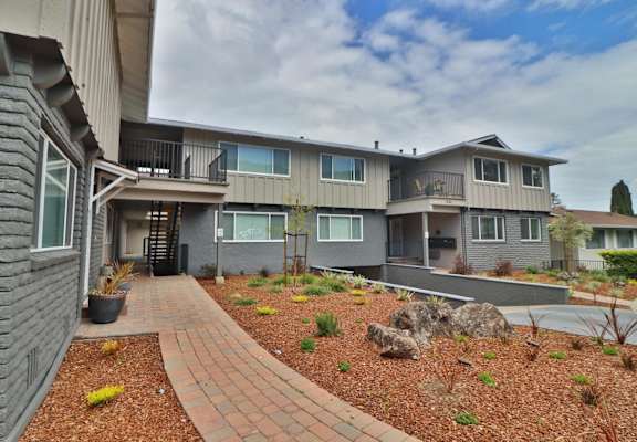 exterior view of apartments with a landscaped yard and walkway
