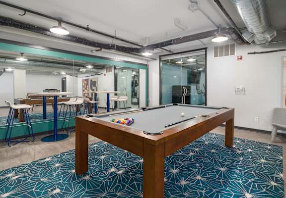 a pool table sits in the middle of a room with a bar in the background