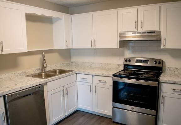 an empty kitchen with white cabinets and stainless steel appliances