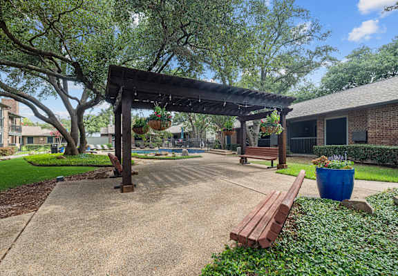 a park with a wooden bench and a pergola