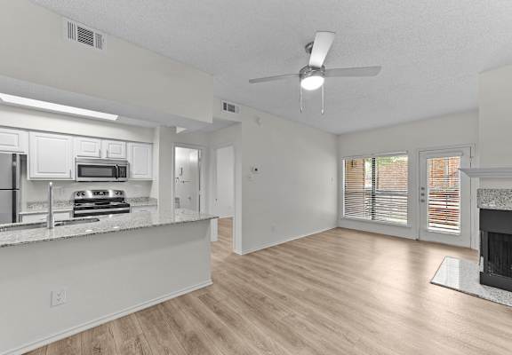 A spacious kitchen with a refrigerator, microwave, oven, and a fireplace in the living room.