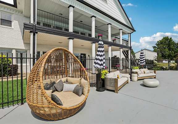 A wicker chair with cushions is in the foreground of a patio area.