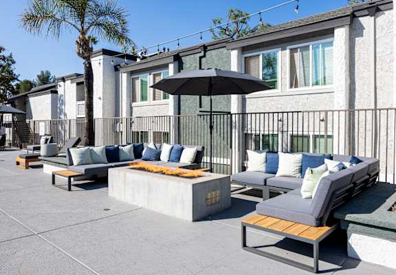 A patio with a black umbrella and grey couches at Verandas Apartments, West Covina, CA, 91791