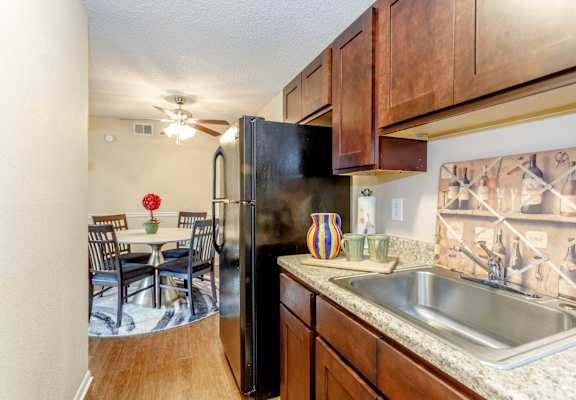 A kitchen with a black refrigerator and wooden cabinets.
