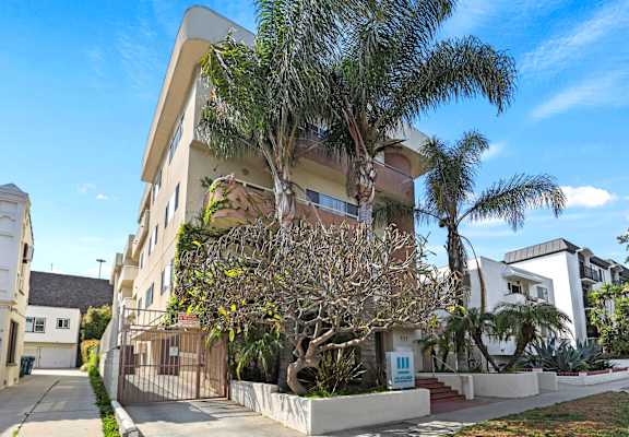 an apartment building with palm trees in front of it