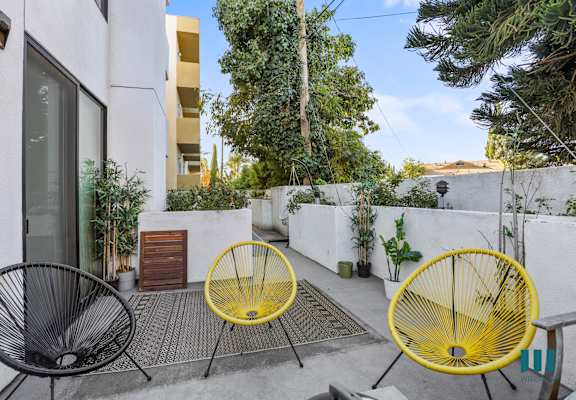 a patio with two yellow chairs and a white wall