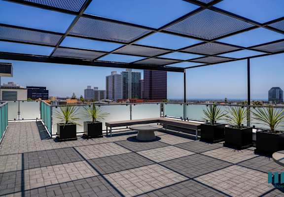 a roof terrace with a view of the city and a bench