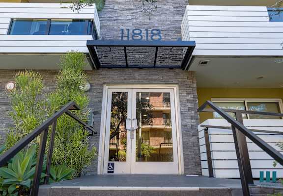 the front of a building with a glass door and stairs