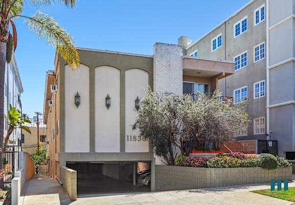 A modern house with a white and beige facade and a palm tree in front.