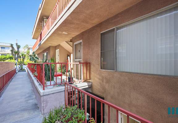 A balcony with red railings and a concrete floor.
