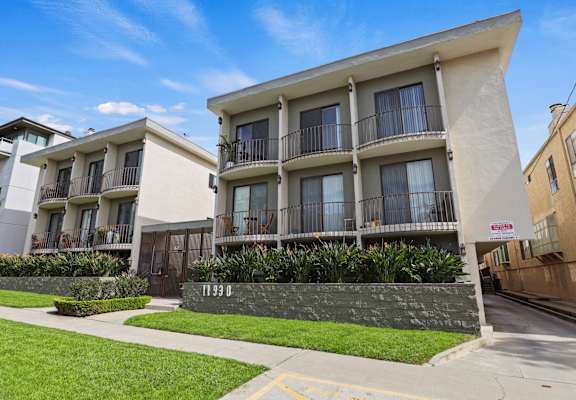 Apartment building with balconies and a green lawn in front.