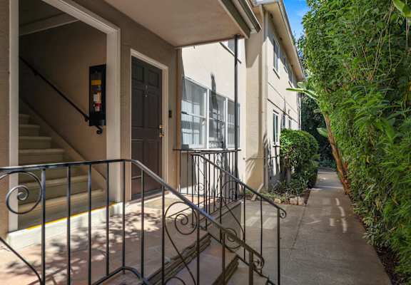 A metal railing on a concrete walkway leads to a building entrance.