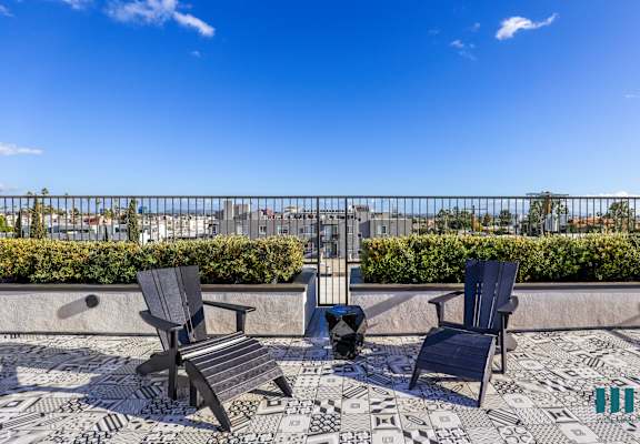 two chairs and a table on a balcony with a view of the city
