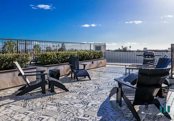 a patio with tables and chairs on a roof with a blue sky
