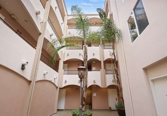A building with a balcony and a tree in the courtyard.