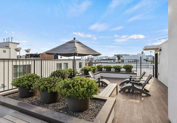 a rooftop patio with tables and chairs and an umbrella