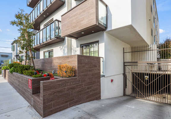 the front of an apartment building with a sidewalk and a gate