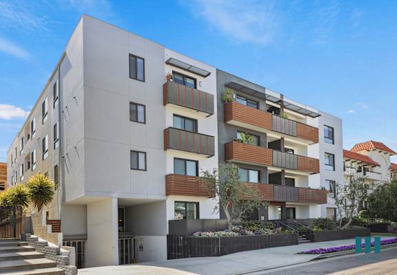 a large white apartment building with balconies and a sidewalk