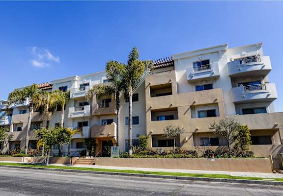 an apartment building on a street with palm trees