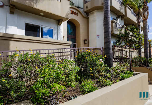 an apartment building with a balcony and plants in front of it