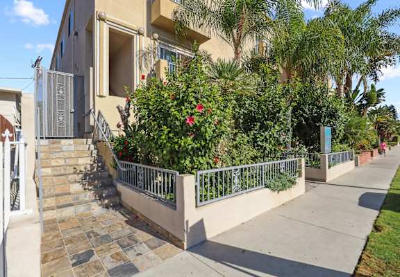 the front of a house with a staircase and plants in front of it
