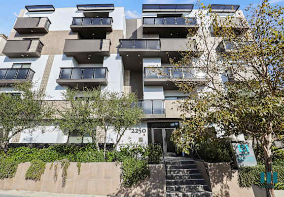 an apartment building with balconies and trees in front of it