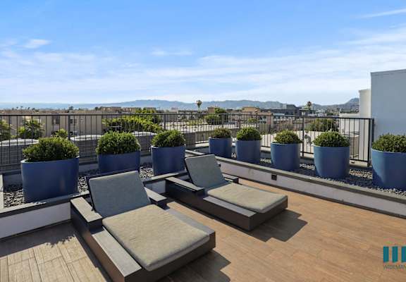 a roof top patio with lounge chairs and potted plants