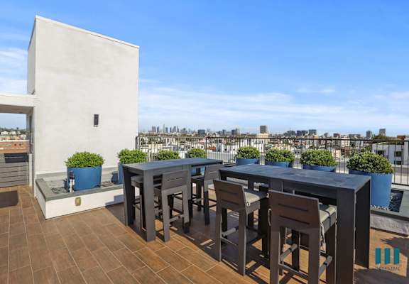 a roof terrace with tables and chairs and a city in the background