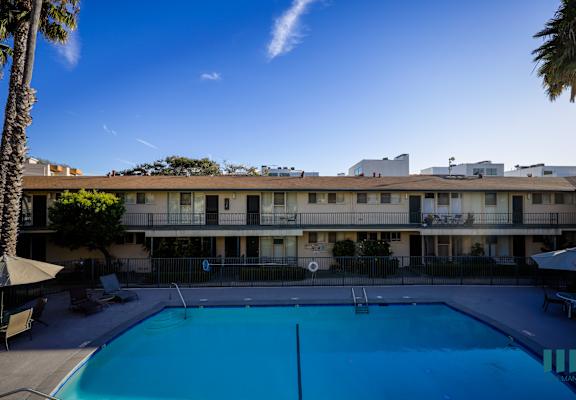 A swimming pool in front of a building with a clear blue sky.